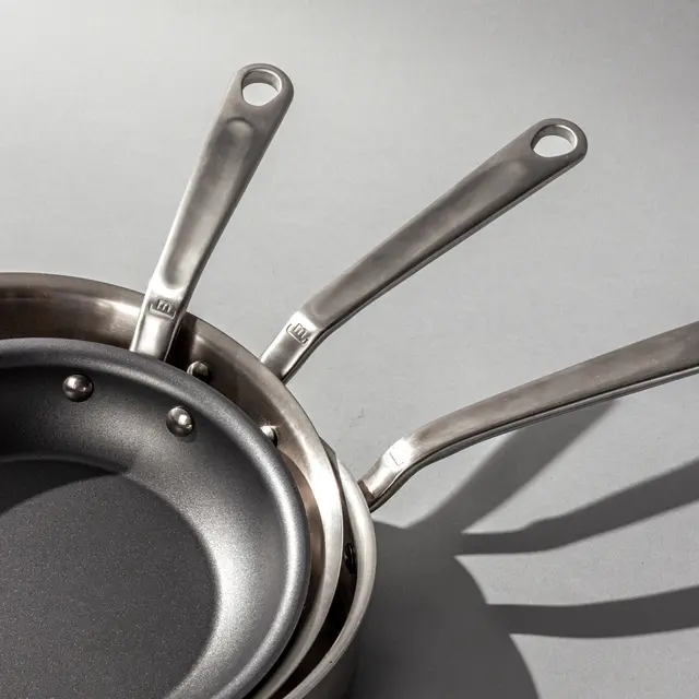 Several pans stacked on a grey background