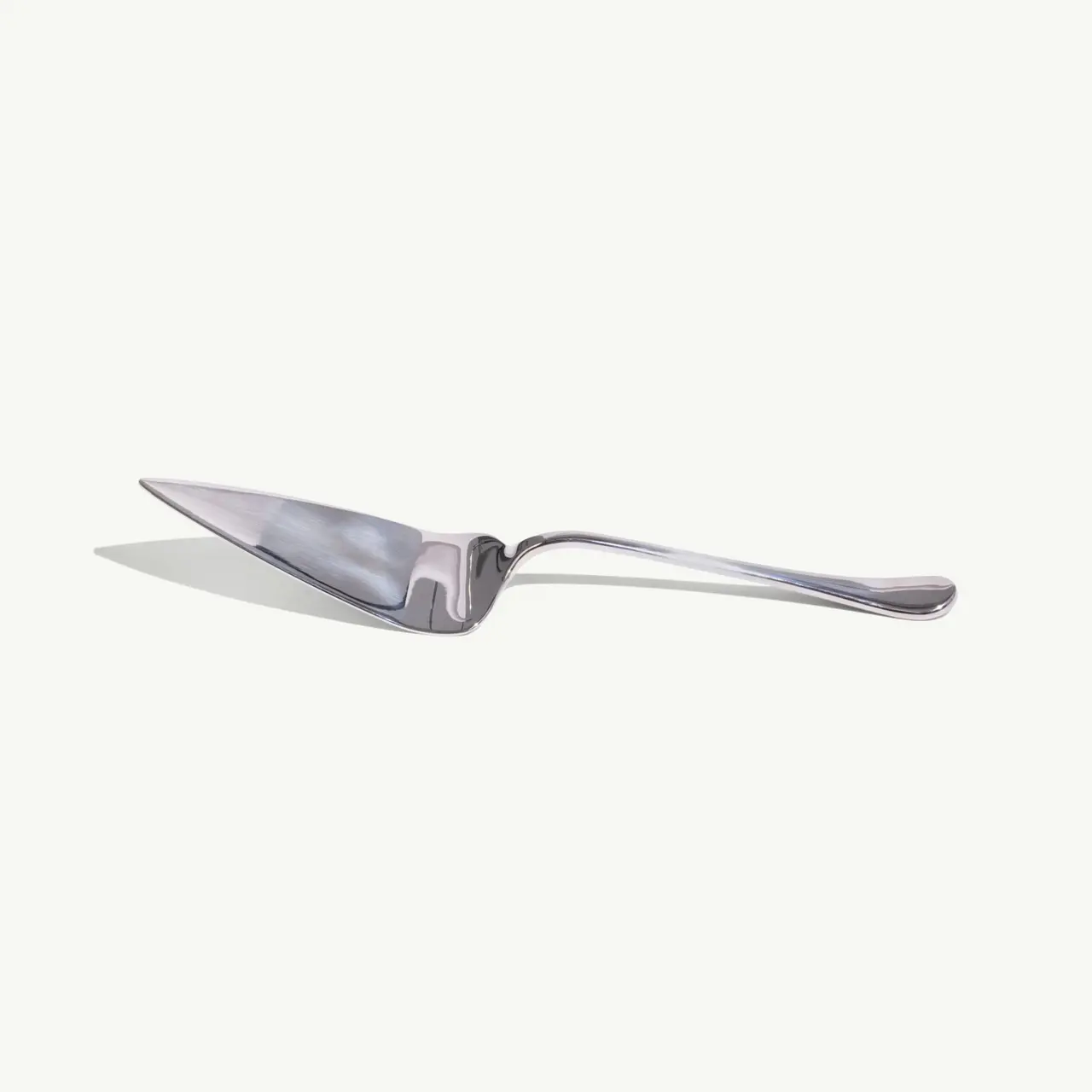 A stainless steel cake server with a triangular blade lies on a light background.