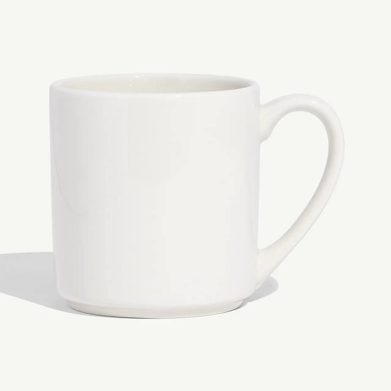 A white ceramic mug with a handle is centered against a plain background.