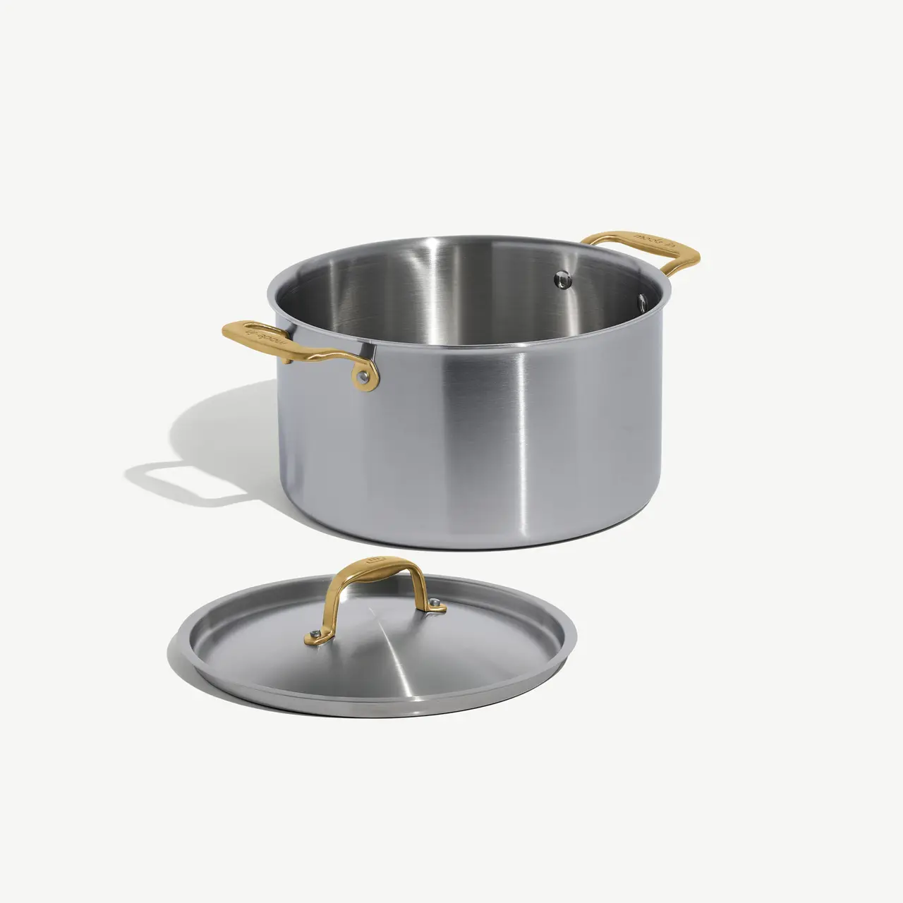 A stainless steel cooking pot with a lid, featuring gold-colored handles.